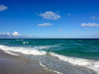 Fototapeta na wymiar Atlantic Ocean off South Beach in Miami, Florida with blue water, some puffy clouds and white surf