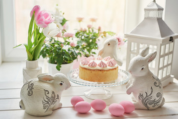 Obraz na płótnie Canvas Easter composition with sweet bread, kulich and eggs with rabbits. Easter holidays breakfast concept with copy space. Easter Greeting Card Template. Easter eggs with cake on white wooden table