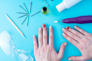 Tools for professional hardware manicure and women's hands on blue background