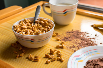 Breakfast with cereals in a bowl with milk, cocoa and banana
