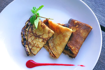 Crepes folded in quarters with fresh fruit, berry coulis and fresh mint