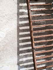 Detail eines verrosteten Gitters vor Hauswand
