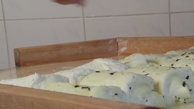 Close-up of making traditional Halloumi Cyprus cheese as salt and mint are added to flavor