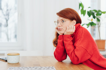 Glum young woman sitting at her dining table