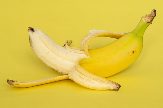 Peeled banana on yellow background