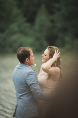 Beautiful wedding couple, bride,groom kissing and posing on the bridge near lake