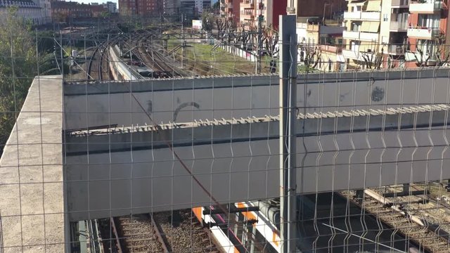 Renfe train exits Barcelona Sants Mercat Nou station disappearing between buildings