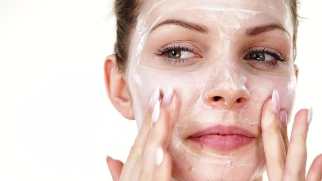 Young woman applying mask moisturizing skin cream on face. Girl taking care of her complexion layering moisturizer. Skincare spa treatment