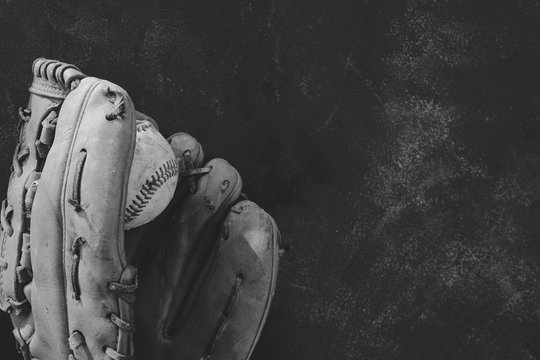 Black and white baseball image with old vintage ball in used grunge leather mitt. 