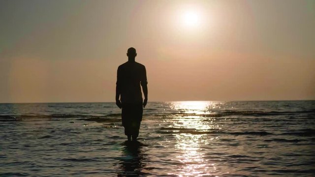 Martial artist practicing wushu routine on the beach at sunset in slow motion, 50 fps.