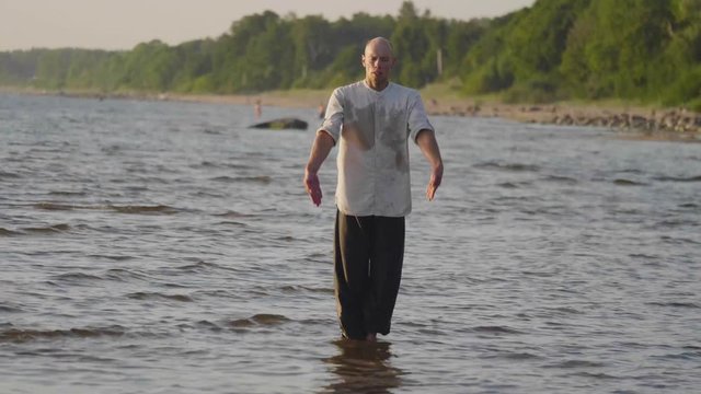 Martial artist practicing wushu routine on the beach at sunset in slow motion, 50 fps.