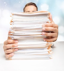 Young businessman with stack of papers on background
