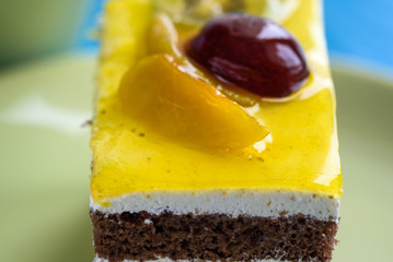 Biscuit cake with fruit tops photographed close-up on wooden background.