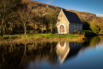 Autumnal mirror reflections of St. Finnbarr's oratory on Gougane Barra lake in West Cork.