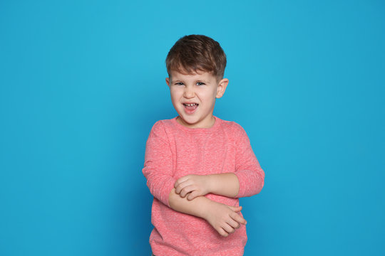 Little boy scratching arm on color background. Annoying itch