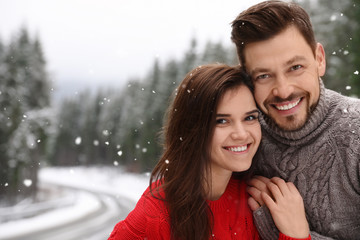 Cute couple outdoors on snowy day, space for text. Winter vacation