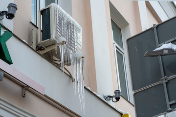 Street block conditioner frozen and covered with icicles and snow in winter