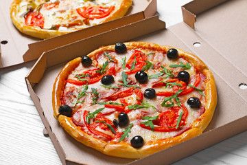 Cardboard boxes with tasty pizzas on wooden table