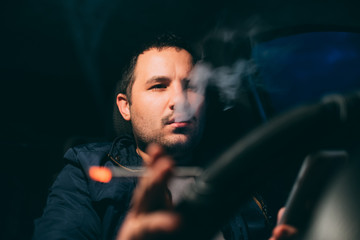 driving with a cigarette in hand, a man Smoking behind the wheel