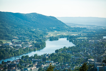 Fototapeta premium Panoramic top view of Drammen city, mountains in fog and valley with river, sunny weather. Norway