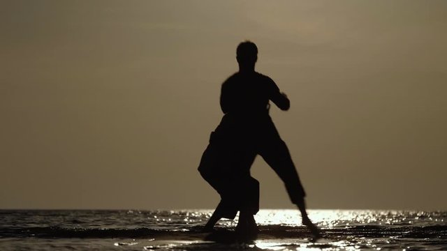 Martial artists friendly sparring on the beach at sunset in slow motion, 50 fps.
