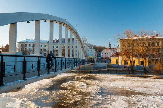 Pedestrian bridge Kaarsild, Emajõgi river and the view on the Town Hall during winter in Tartu, Estonia. Man is riding the bicycle