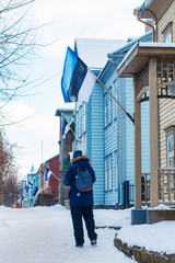 Young man walking down the street of Karlova district of Tartu, Estonia, decorated with national flags during celebration of 100 years of Estonian independence 24 Feb. 2018
