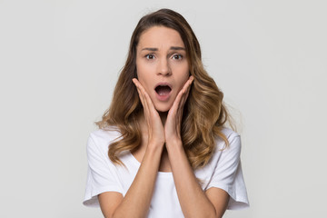 Shocked woman feeling terrified looking at camera on white studio wall, stressed horrified frightened lady in panic with scared face screaming having phobia posing on light blank background, portrait