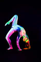 Female dancer in bright neon colours under ultraviolet light on background.