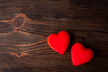 Red hearts on dark wooden background.