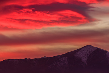 a spectacular red cloud above the mountains /a landscape at sunset with mountains  drawn in the sky