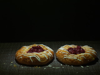 Two sweet cheesecakes with cherries are on the tablecloth.