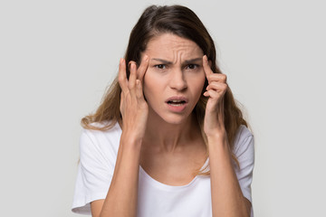 Stressed young woman confused about facial wrinkles aging skin on forehead or crows feet looking at...
