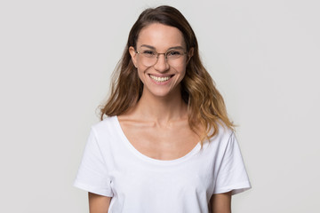 Fototapeta premium Happy young woman wearing optical glasses for sight vision correction looking at camera on white background, smiling pretty girl student in eyeglasses posing isolated on blank studio wall, portrait