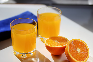 Freshly squeezed orange juice in glass cups and fresh oranges.