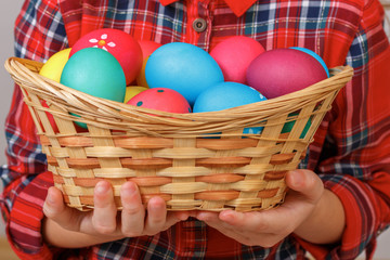Fototapeta na wymiar Little kid girl holding a basket of Easter eggs. Close-up