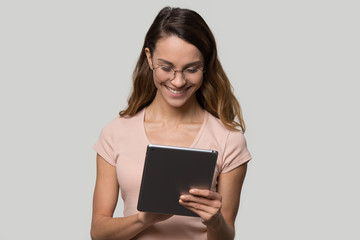 Happy teen girl using digital tablet surfing online content chatting in social media, smiling young woman user shopper consumer holding pc doing shopping online isolated on blank studio background