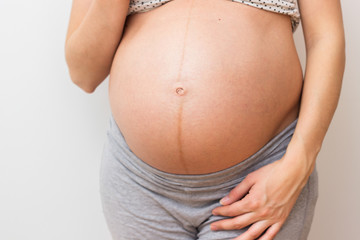 Pregnant woman standing next to wall
