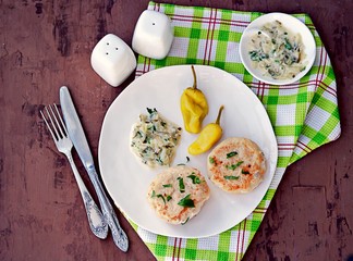 Homemade fish cakes on a white plate. Served with tartar sauce and marinated hot pepper.