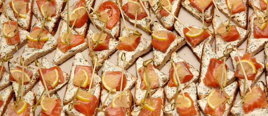 Closeup of canapes with cream cheese, salmon, greens and lemon