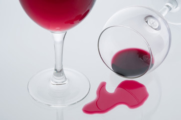Red wine glass and spilled red wine glass on gray background