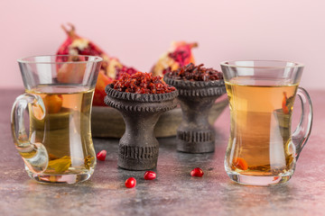 Different varieties of Shisha Smoking hookah. Black annealed ceramic bowl for hookah in the background of tea cups and the open pomegranate.
