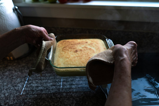 Hands placing fresh cake on cooling rack