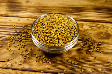 Fenugreek seeds in glass bowl on wooden table