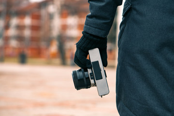 Hipster female photographer holding vintage SLR camera on street