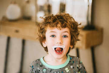 Portrait of boy with milk mustache standing at home