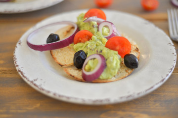 Healthy breakfast. Avocado salad with sherry tomatoes olives and onion on pita bread. On wooden table. flat lay top view copy space 