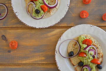 Healthy breakfast. Avocado salad with sherry tomatoes olives and onion on pita bread. On wooden table. flat lay top view copy space 
