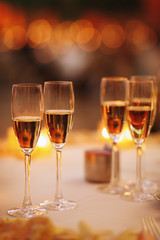 Four glasses with pink champagne stand on the table with shiny candles