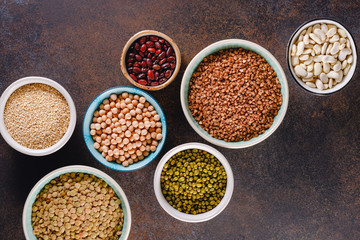 Top view on bowls with various grains on a textured dark background.